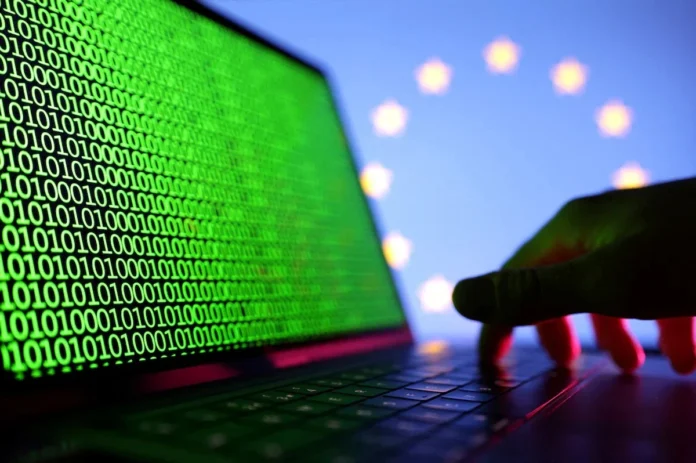 A hand is seen on a laptop with binary codes displayed in front of the EU flag in this illustration taken, August 19, 2022. REUTERS/Dado Ruvic/Illustration/File Photo