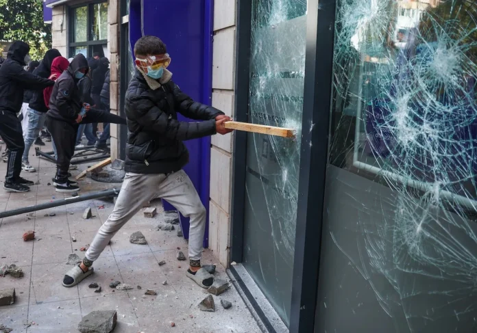 A demonstrator smashes a window during clashes with police amid an anti-government protest by students, in Tirana, Albania, October 15, 2026. REUTERS/Florion Goga