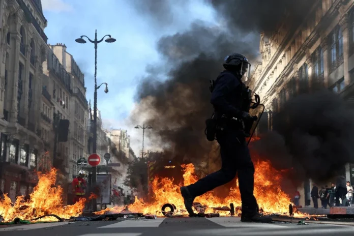 French riot police walk past burning objects in a street amid clashes with protesters in Paris, October 17. REUTERS/Abdul Saboor