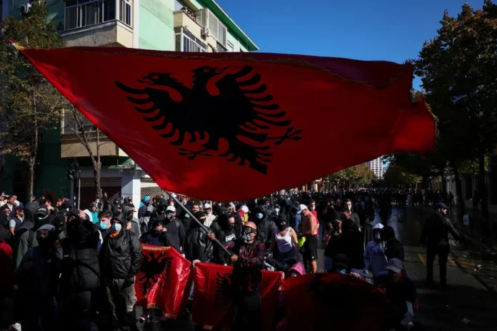 A demonstrator wearing a gas mask waves a large Albanian flag during an anti-government protest by students in Tirana, Albania, October 16, 2026. REUTERS/Florion Goga