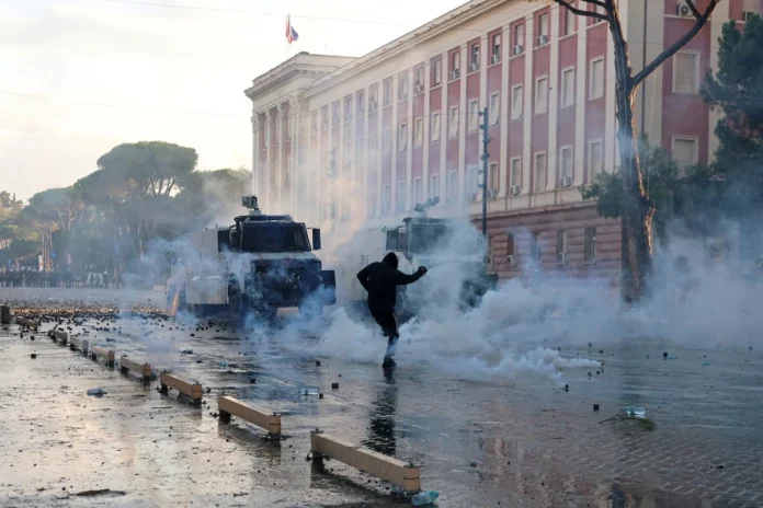 A demonstrator reacts to tear gas near police forces guarding next to the parliament building amid an anti-government protest by students in Tirana, Albania, October 16, 2026. REUTERS/Louisa